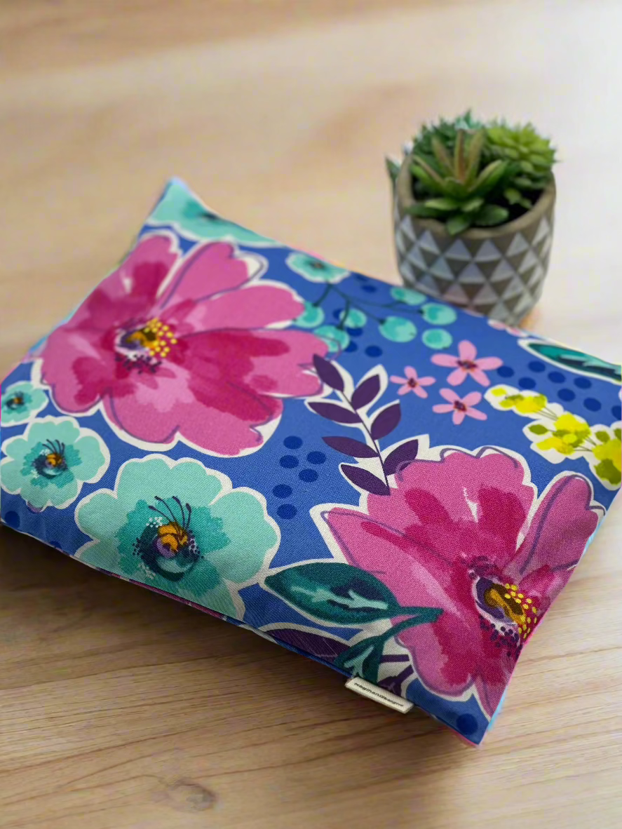 Large pink and turquoise colored flowers printed on blue cotton fabric.
