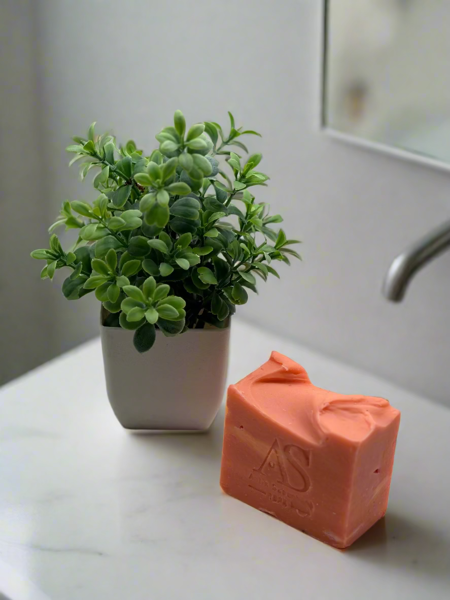 Handmade amber soap, amber color. there is small greens in a vase as a decoration on the side. 