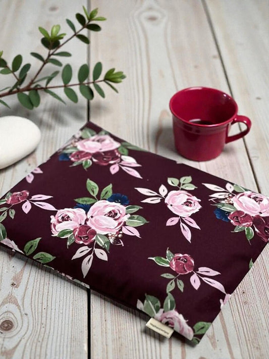 Floral-patterned pouch on a wooden surface with a red mug and plant.