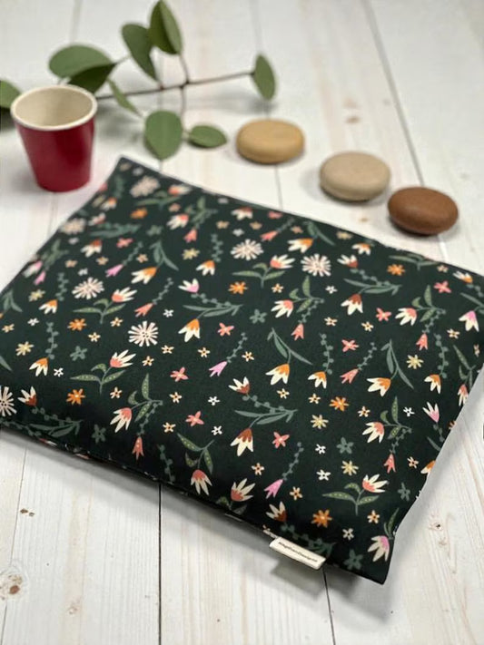 Floral-patterned fabric on a wooden surface with a cup and stones.