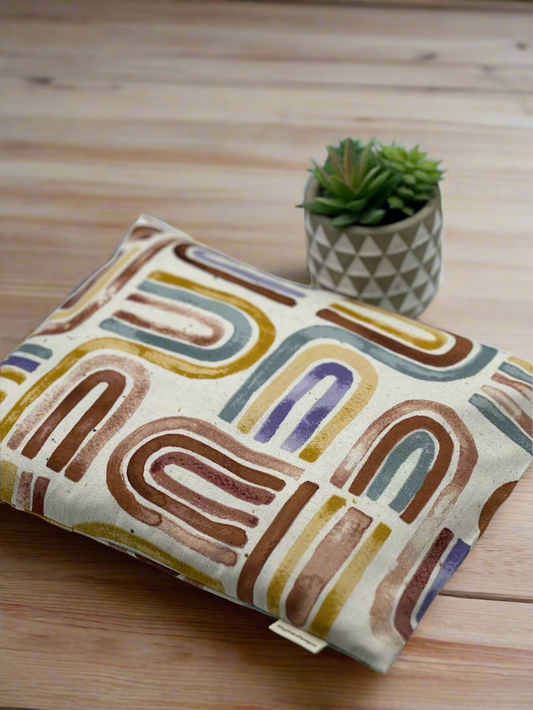 dark Brown, light brow, mustard yellow and green u shapes on drawn on the top of each other printed on a cream cotton fabric corn heating pad