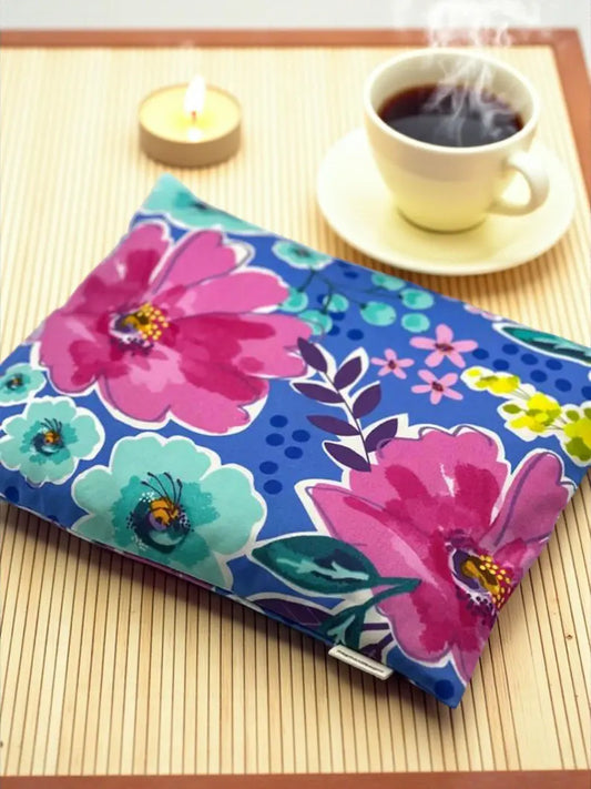Floral-patterned pouch on a table with a cup of coffee and candle