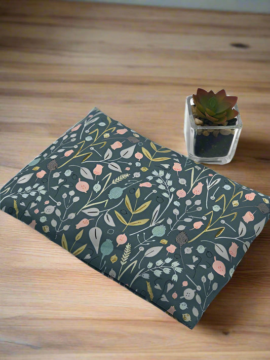 corn heating cooling pad with a green fabric flowers and leaves printed on on a wooden table background 